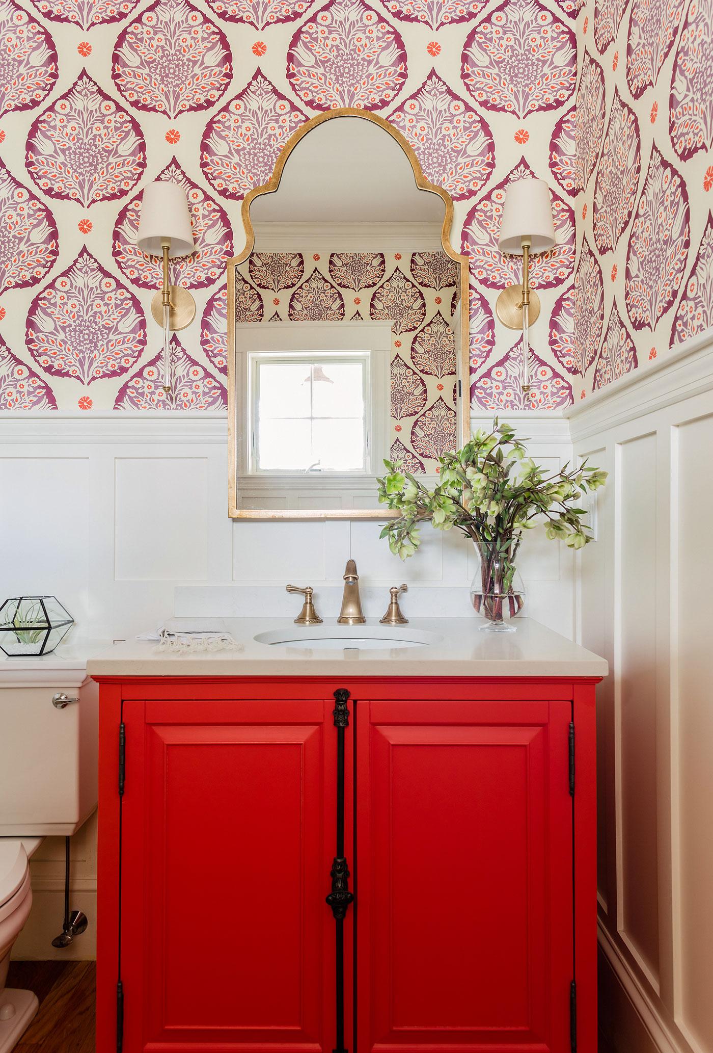 Colorful powder room with red cabinet doors and white paneled walls